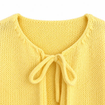 Close-up of V-neckline and tie detail on a yellow knit cardigan