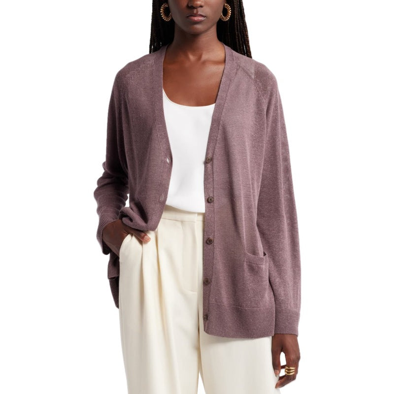 Front view of a woman wearing a custom button knit cardigan in a linen blend, styled open over a white top. The mauve cardigan features a relaxed fit with two front pockets. She pairs it with white pants and hoop earrings, creating a casual yet elegant look.