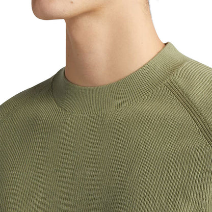 Close-up of the neck and shoulder area of a custom 100% cotton knit sweater in olive green, showcasing the fine ribbed crew neck and fabric texture.