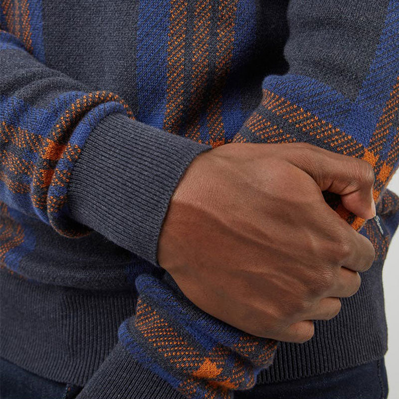 Close-up of the sleeve and cuff of a custom cotton blend knit sweater, showing the detailed jacquard geometric figure design in navy blue and orange.