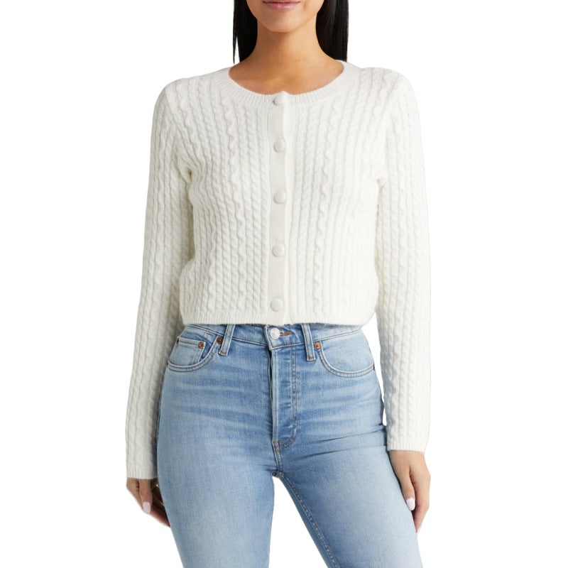 Model wearing a white cable knit cardigan paired with blue jeans. The sweater features a crew neck design and front button closures, showcasing a casual yet stylish look.