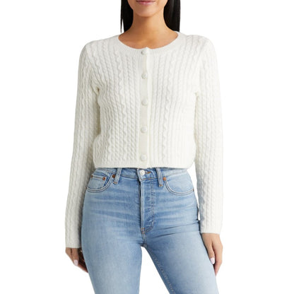 Model wearing a white cable knit cardigan paired with blue jeans. The sweater features a crew neck design and front button closures, showcasing a casual yet stylish look.