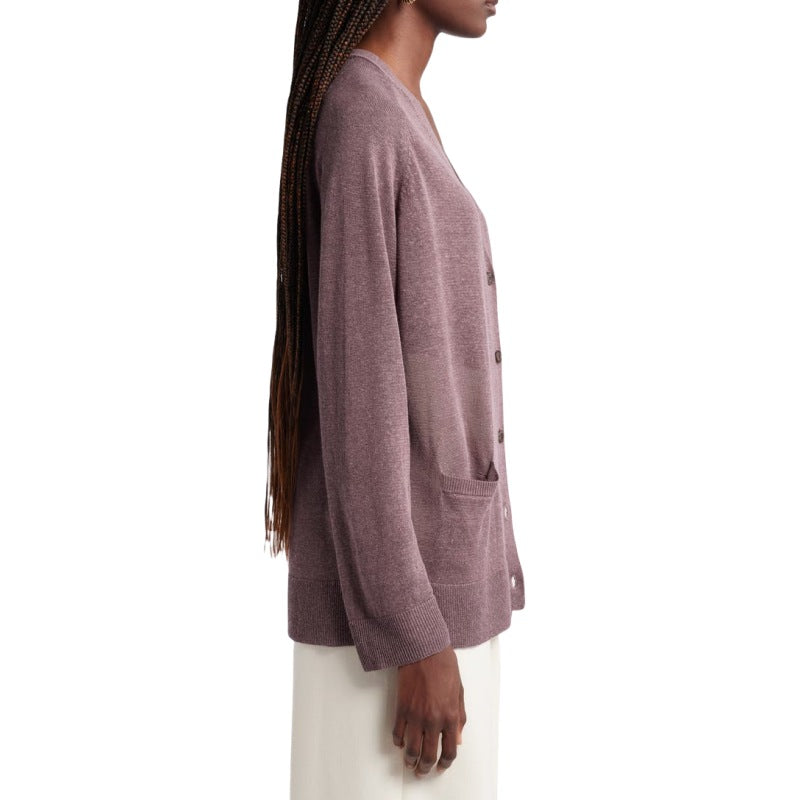 Side view of a woman wearing a custom button knit cardigan in a linen blend. The mauve cardigan has a relaxed fit, showing the details of the side seam and long sleeves. She has long braids and is styled with white pants and hoop earrings.