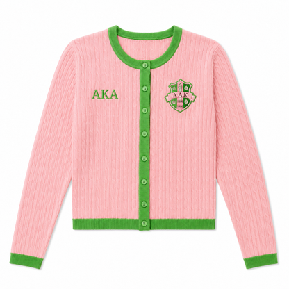 AKA salmon pink cable-knit cardigan with apple green trim, buttons, and Greek-inspired crest