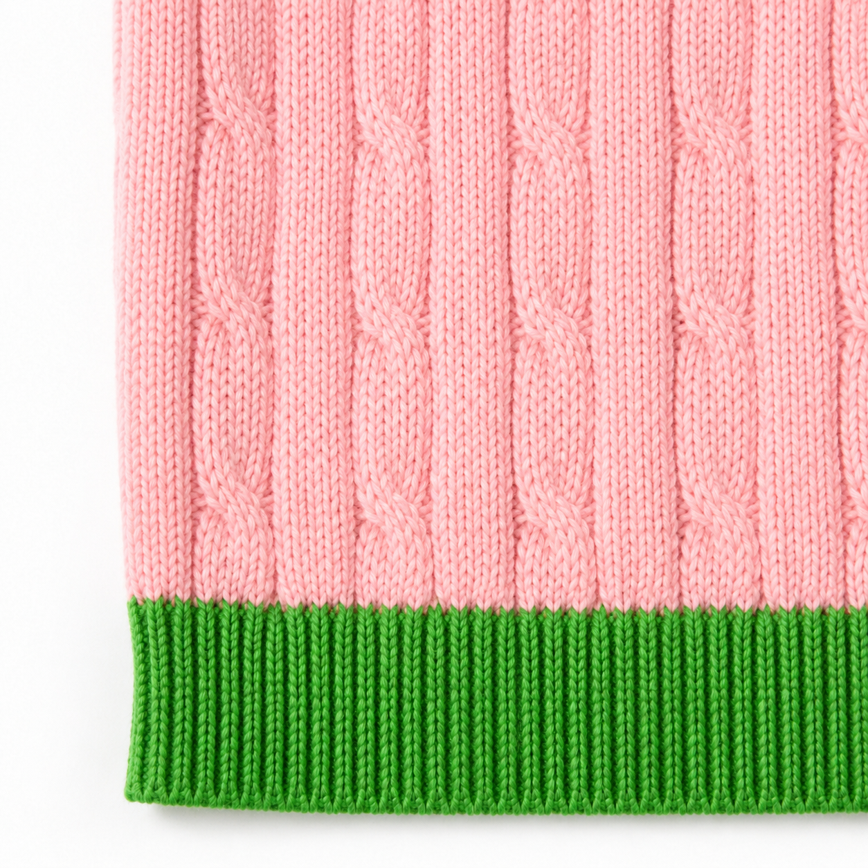 Macro view of salmon pink vertical cable-knit texture with detailed green ribbing