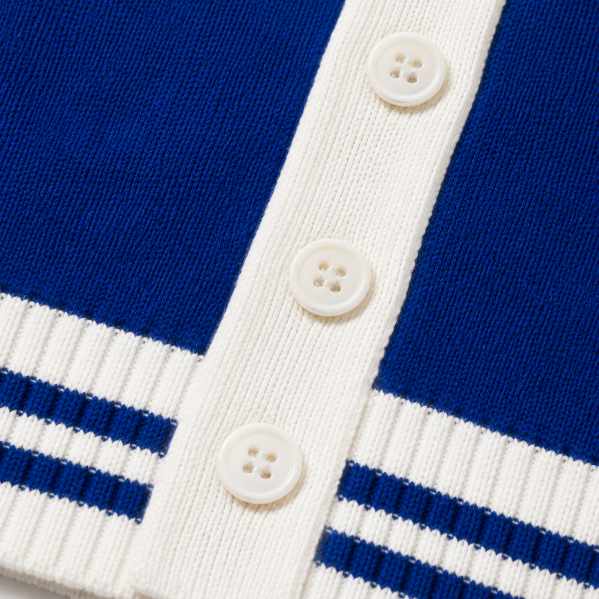  Macro view of royal blue knit texture, white ribbing, button details, and blue stripe construction
