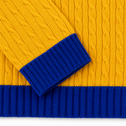 Detailed view of textured yellow knit sweater with royal blue striped cuffs and ribbed hem finish