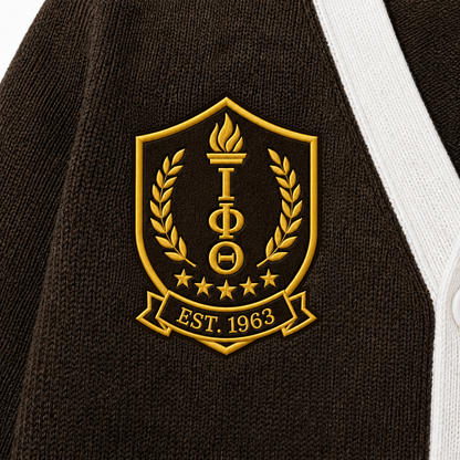 Close-up brown knit texture with ornate gold ΙΦΘ shield, 1963 detail, fine stitches and white cardigan trim