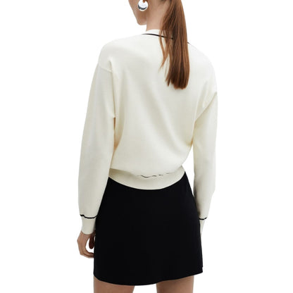 Stylish rear perspective of a white knit cardigan with black trim, showing a sleek and modern look when paired with a black skirt.