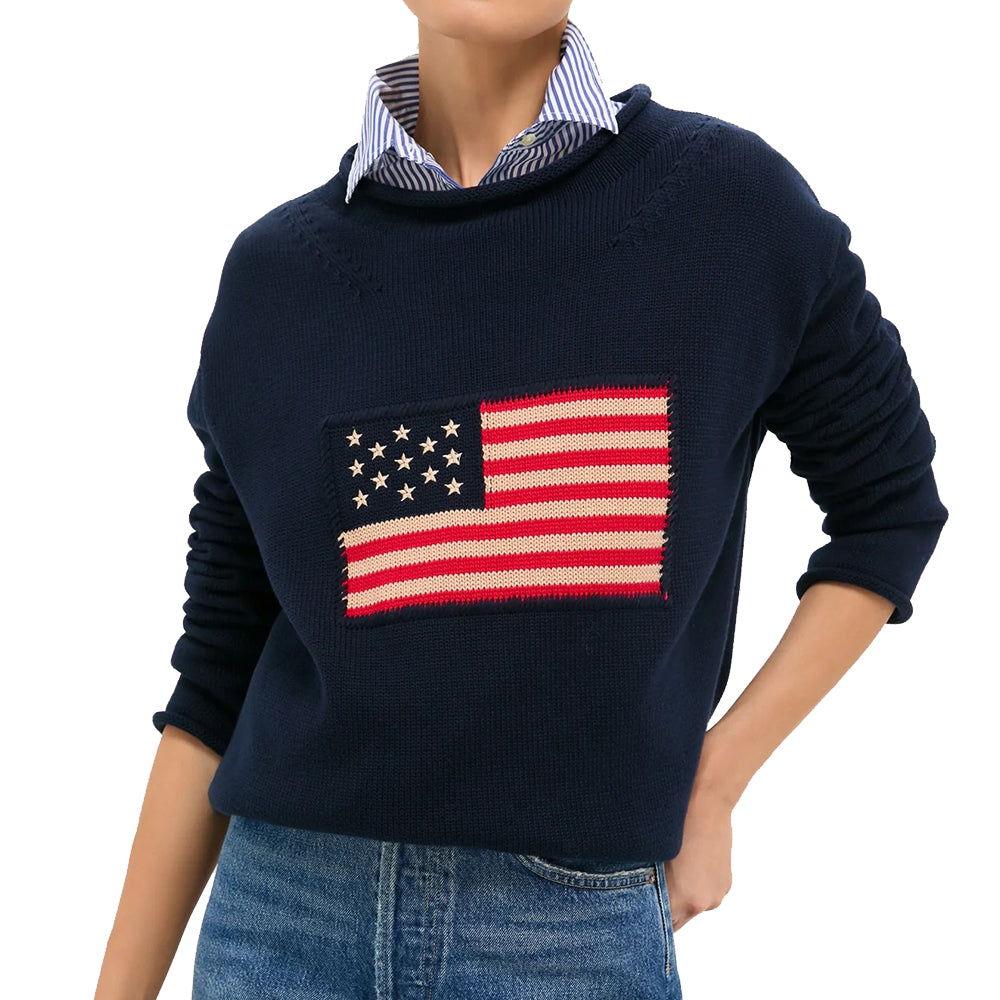 Navy relaxed crew-neck sweater with a knitted American flag chest motif, styled over a striped shirt.