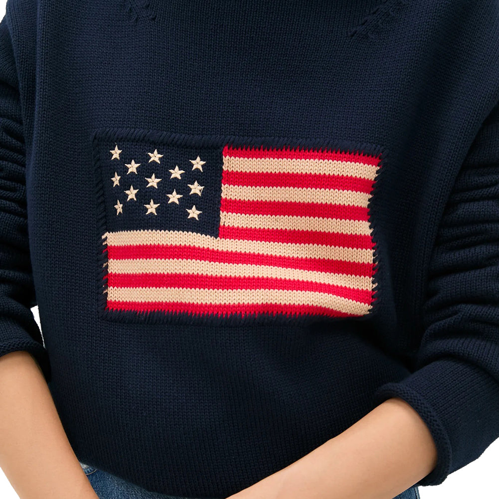 Close-up of a navy knit sweater showing a red, cream and navy American flag chest motif.