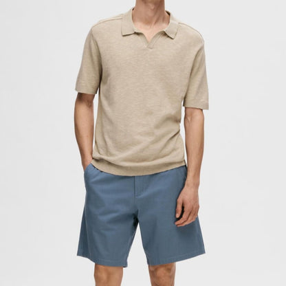 Model wearing custom plain short sleeve knit polo shirt in beige with blue shorts