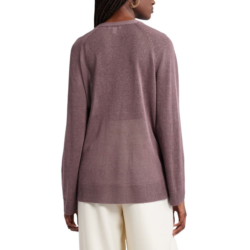 Back view of a woman wearing a custom button knit cardigan in a linen blend. The mauve cardigan has a simple, seamless design at the back, paired with white pants and hoop earrings. Her long braids are visible from the back.