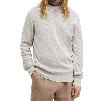 Front view of a light grey knit sweater made of 100% cotton, worn by a model with long hair. The sweater features a simple, casual design.