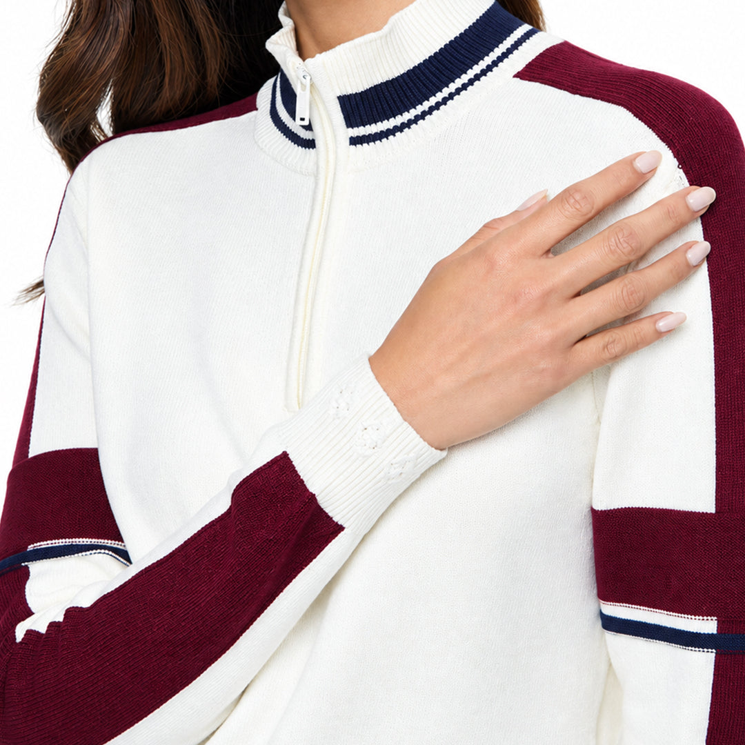 Close-up of the burgundy sleeve and striped cuff detail on a white women's knit sweater