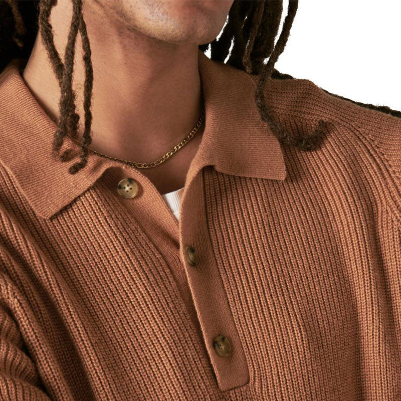 Close-up of the camel-colored ribbed knit polo sweater, focusing on the button placket and collar detail, worn by a man with dreadlocks.