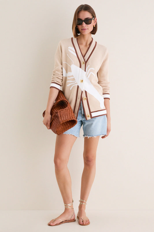 Women's beige cardigan with white motif pattern styled with denim shorts.