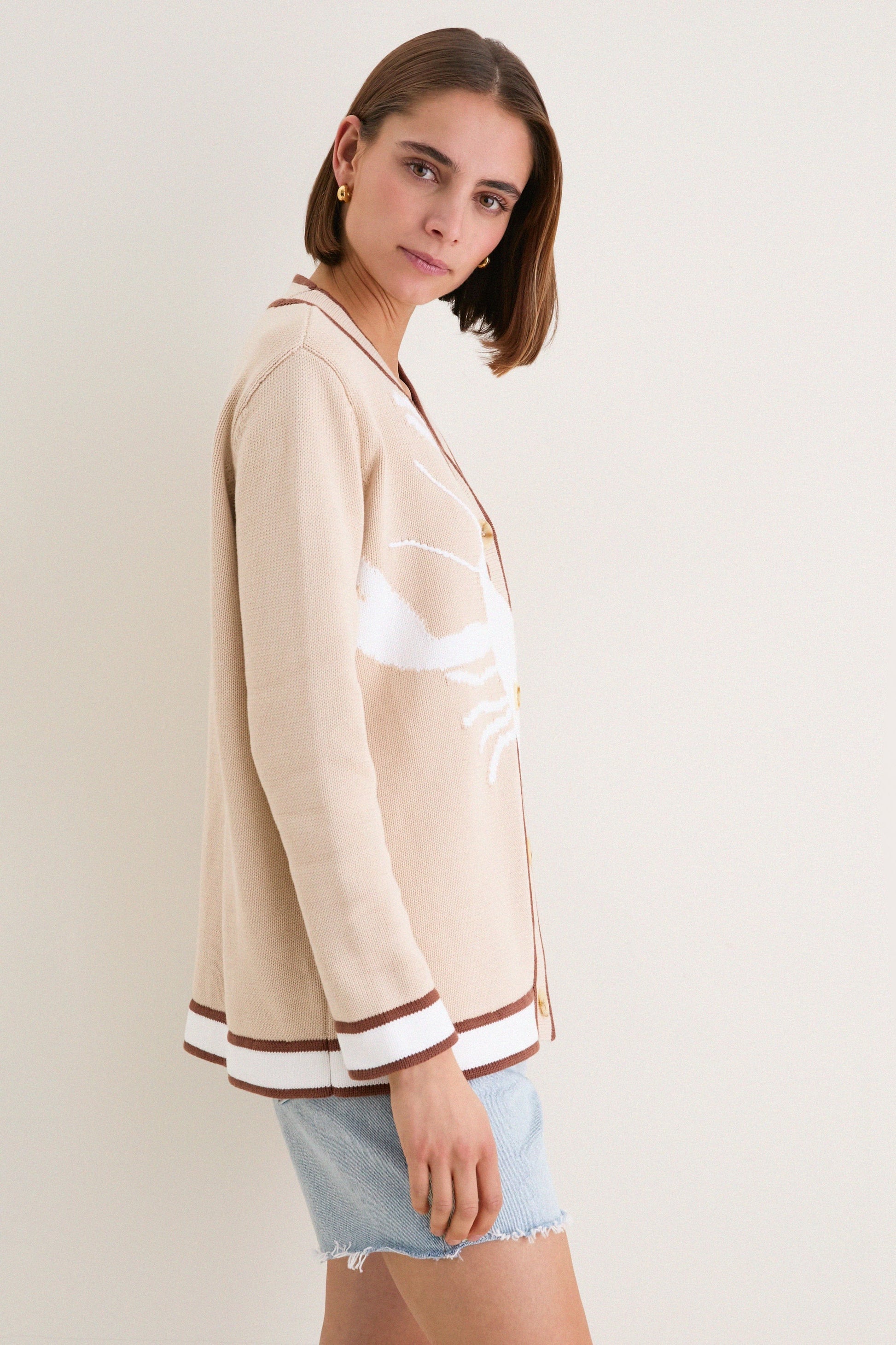 Side view of women's beige cardigan with contrast brown edges and long sleeves.