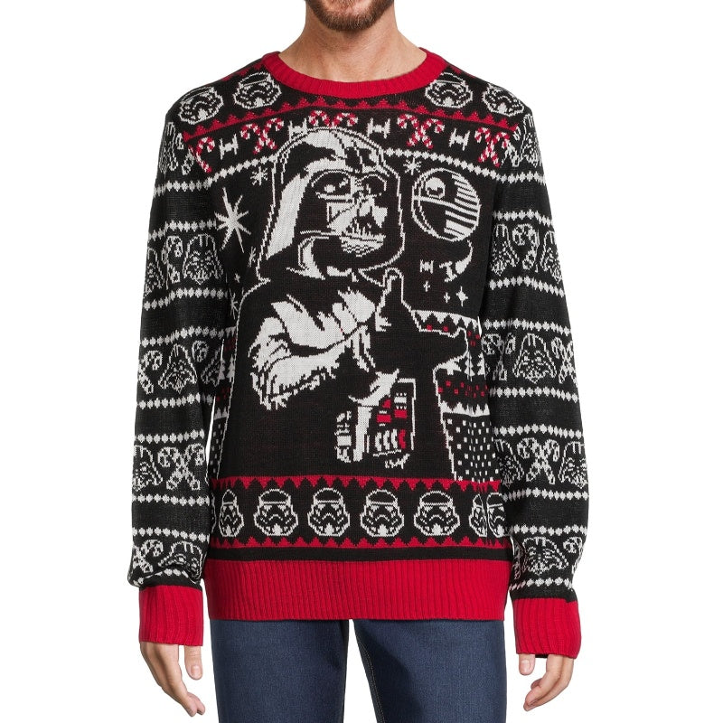 Front view of a man wearing a black pullover sweater featuring a Darth Vader design with red accents, stormtroopers, and TIE fighters in a festive holiday pattern.