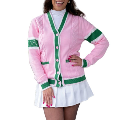Happy woman in a custom 100% cotton pink cardigan with green and white stripes, featuring the number '08' on the sleeve. She is paired with a white pleated skirt, smiling and posing in a relaxed manner, exemplifying casual, trendy outerwear.