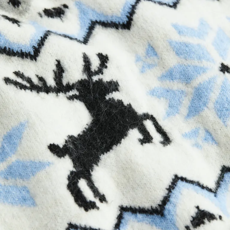 Close-up of a custom jacquard knit sweater showcasing the detailed reindeer and snowflake pattern in white, blue, and black colors, highlighting the intricate winter motifs and high-quality craftsmanship.
