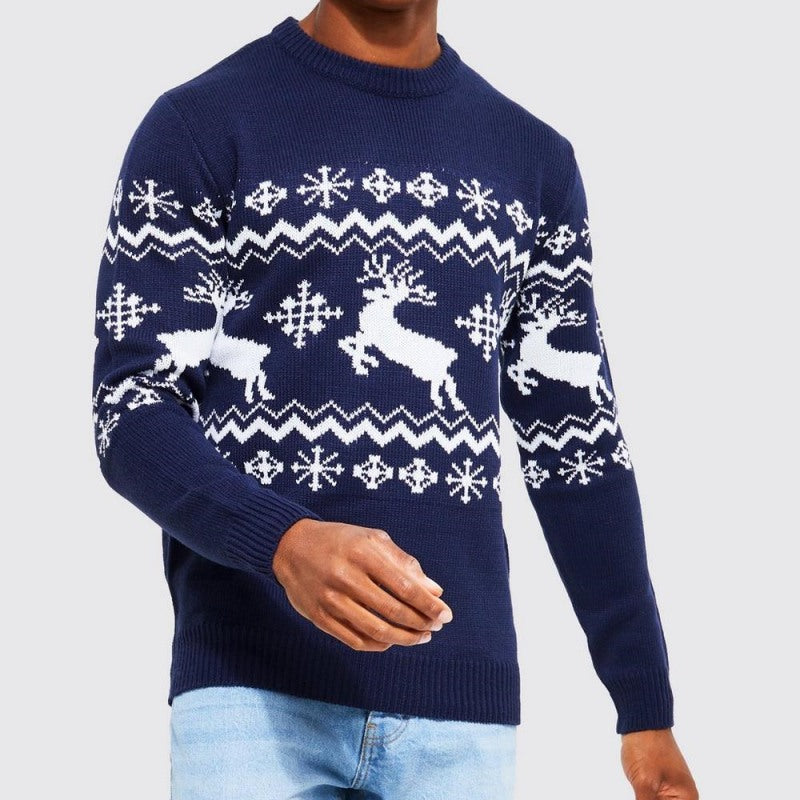 "Model wearing a custom cashmere Christmas sweater with a navy reindeer Fair Isle pattern, paired with light blue jeans. The sweater features white reindeer and snowflake motifs, perfect for festive and winter occasions."
