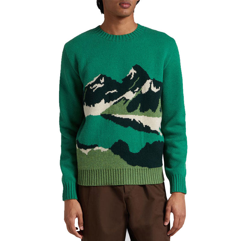 Model wearing a green wool blend pullover knit sweater with mountain jacquard, front view.