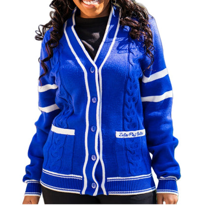 A person wearing a bright blue cardigan with white trim and buttons, featuring white stripes on the sleeves and "Zeta Phi Beta" embroidered on the left pocket.